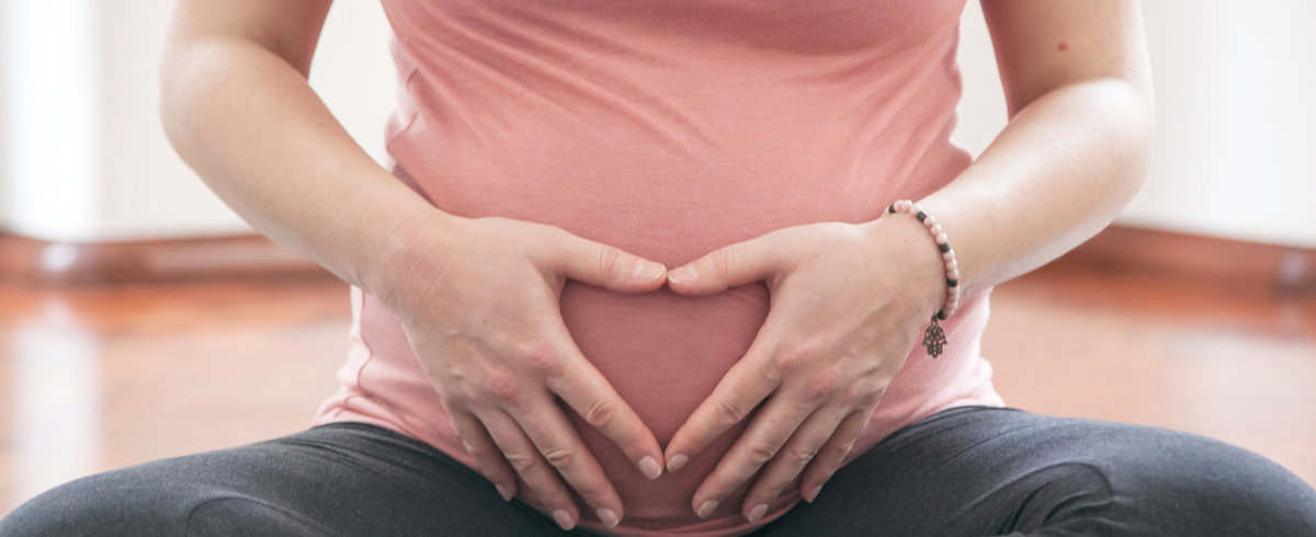 Pregnant woman resting her hands on her bump